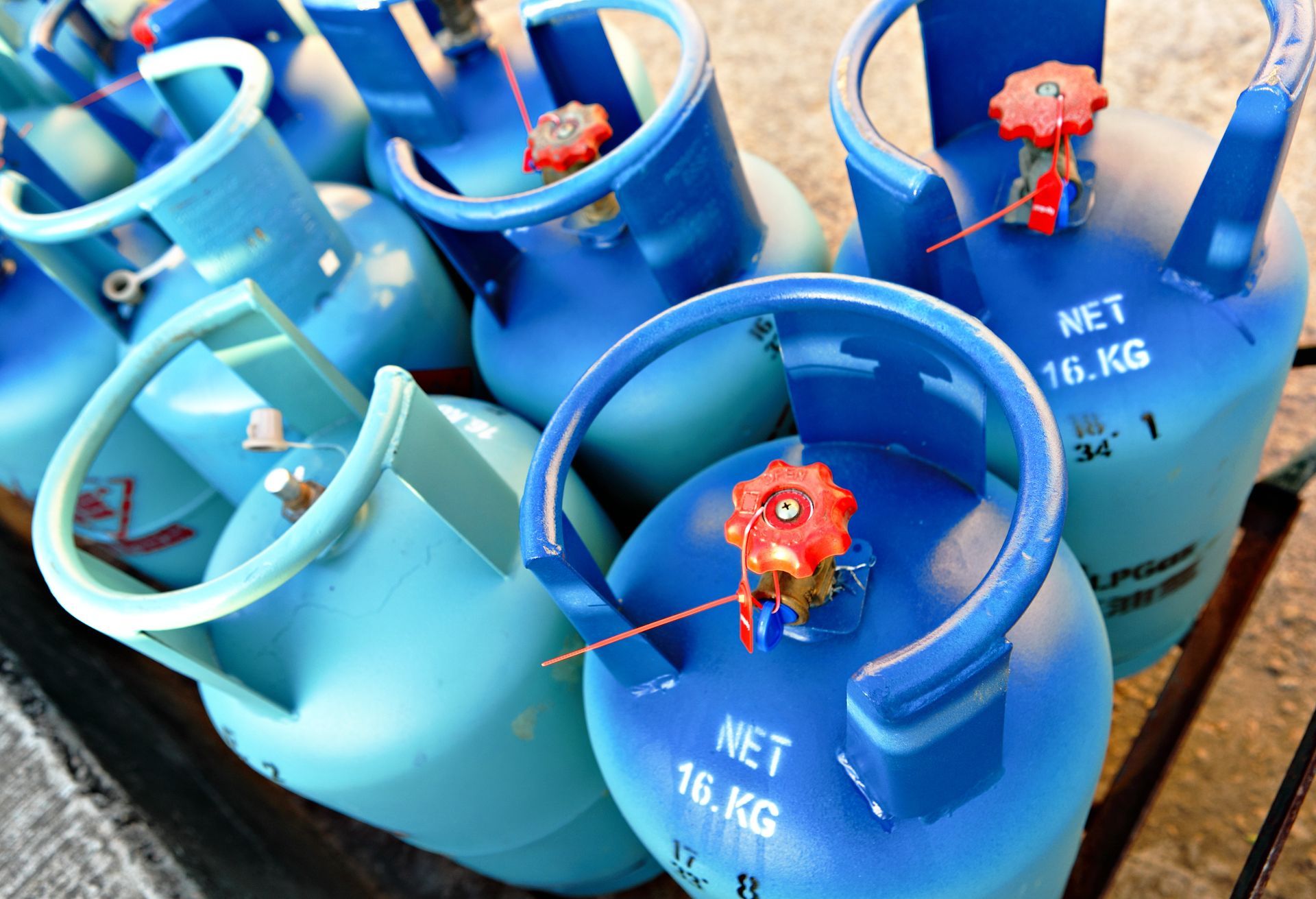 Bouteilles de gaz GPL bleues à valves rouges, posées sur une palette en bois