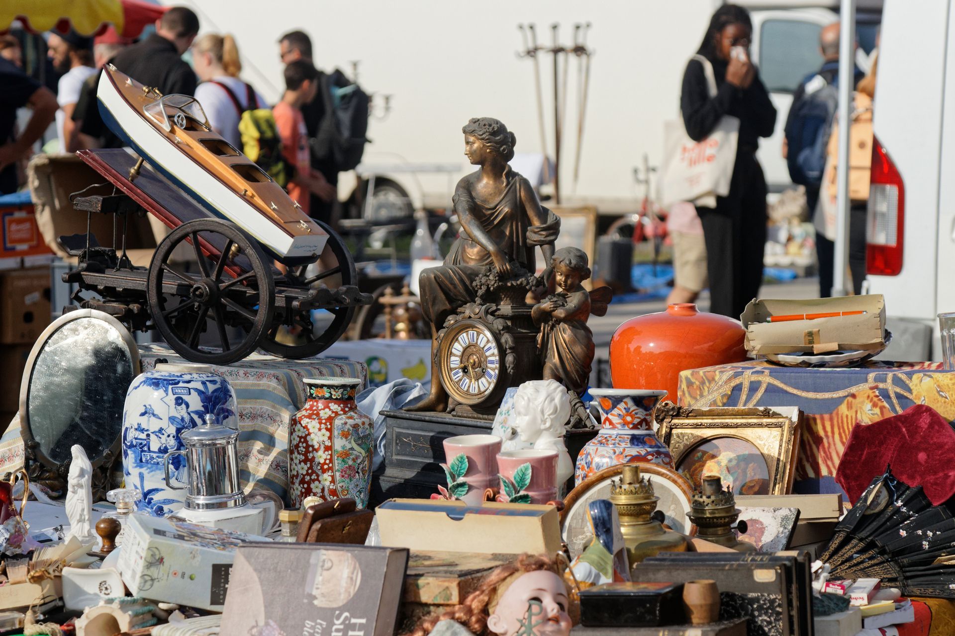 Une table de marché aux puces en plein air avec de nombreux bibelots et céramiques.