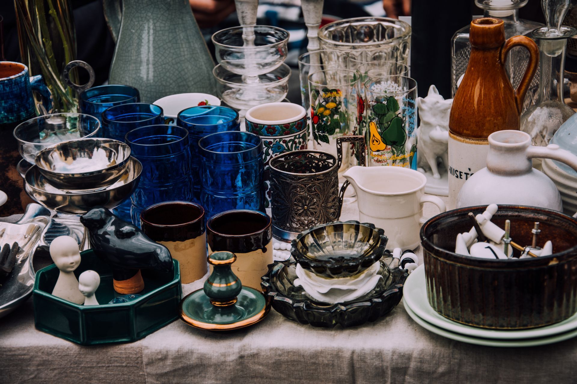 Assortiment de verrerie et de vaisselle en céramique vintage exposé sur une table en plein air