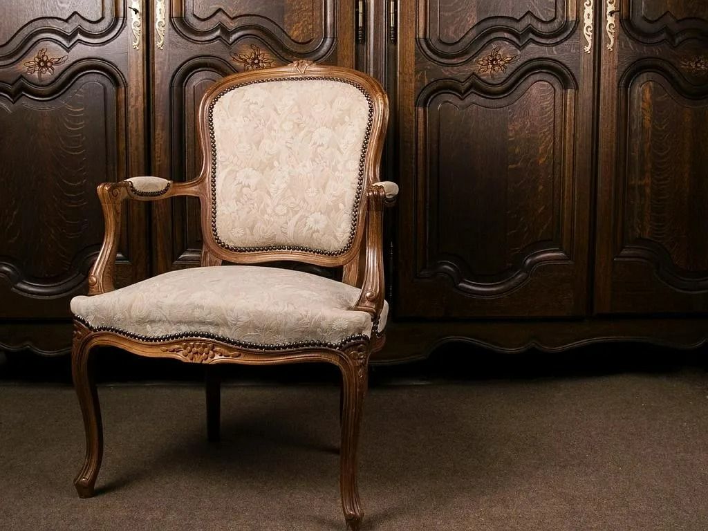 Fauteuil capitonné beige devant un meuble en bois sculpté sombre