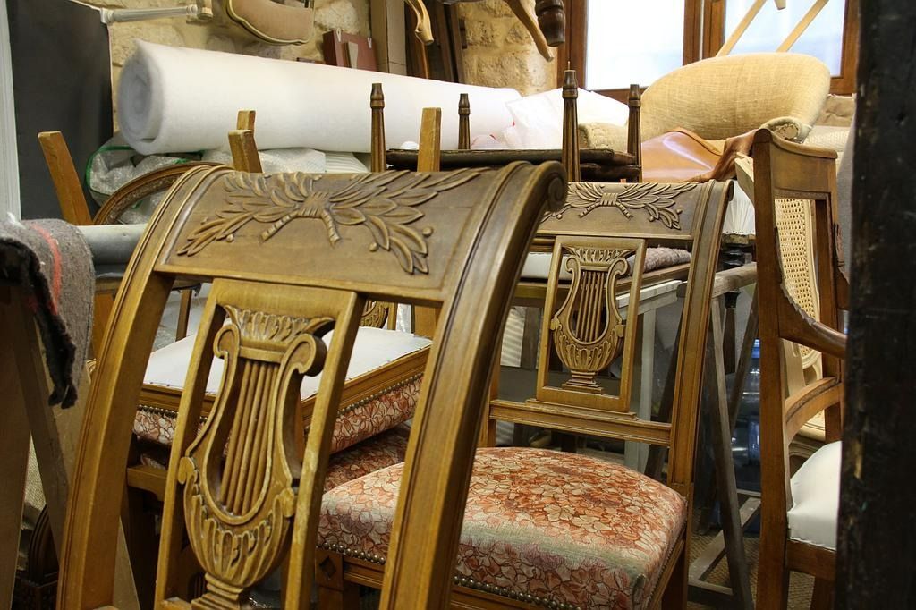 Chaises décoratives en bois avec assises en tissu usées et abîmées dans une pièce encombrée