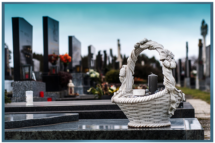 Tombe avec pierres tombales et panier décoratif avec des bougies, ambiance sombre.