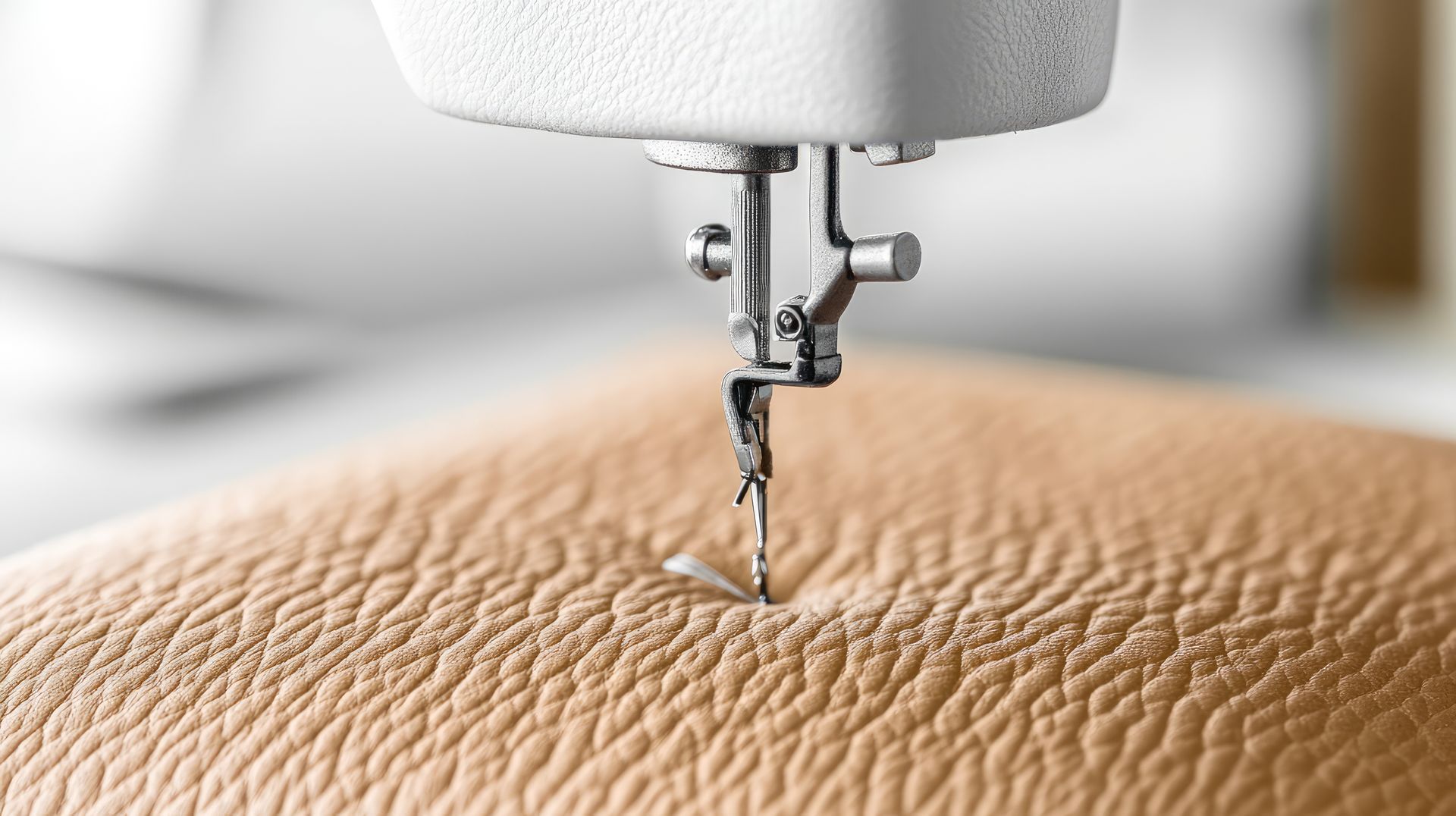 Gros plan d’une aiguille de machine à coudre qui pique un tissu beige texturé