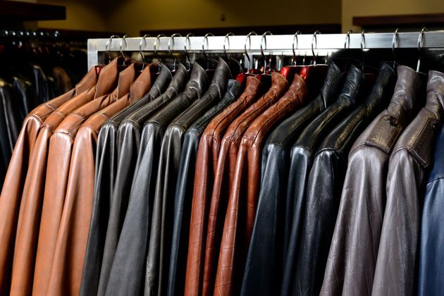 Rangée de vestes en cuir suspendues sur un portant en magasin, dans des tons bruns, noirs et gris