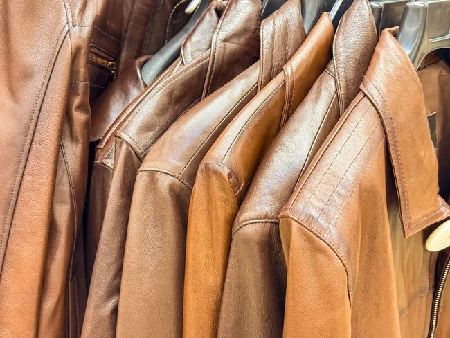 Vestes en cuir marron suspendues à un portant à vêtements
