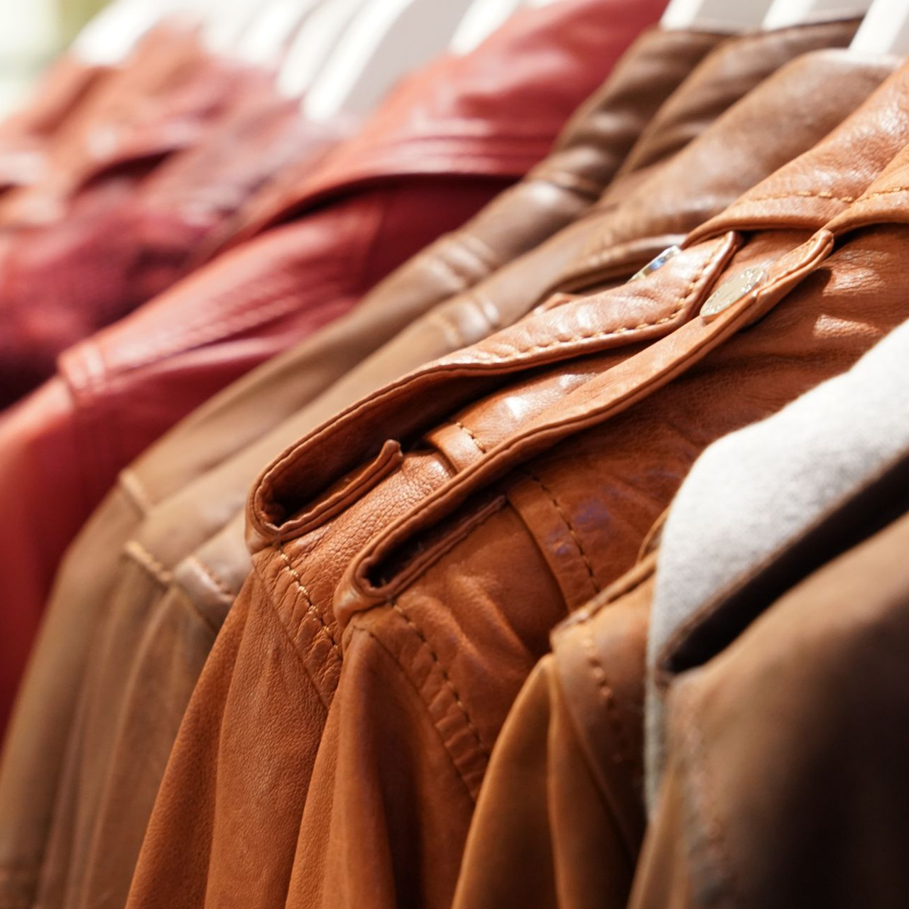 Rangée de vestes en cuir suspendues, dans des tons bruns, camel et rouges