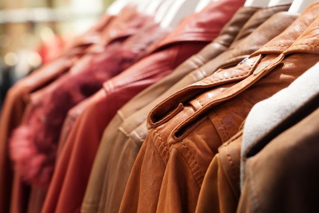 Rangée de vestes en cuir suspendues, dans des tons bruns et rouges, exposées dans un magasin de vêtements