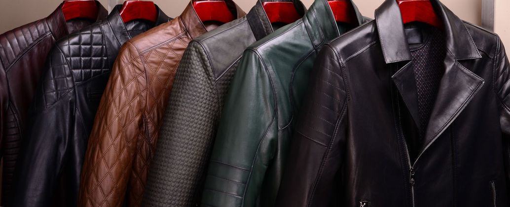 Rangée de vestes en cuir suspendues sur un portant, en noir, marron, gris et vert