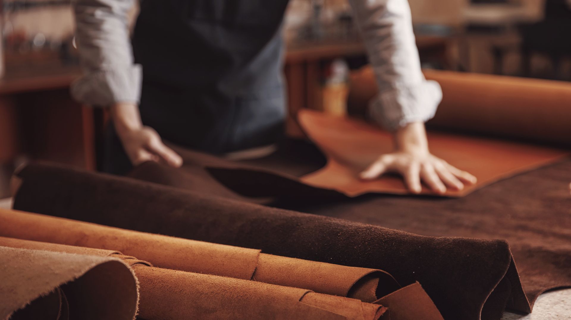 Personne disposant des rouleaux de tissu marron sur une table dans un atelier textile