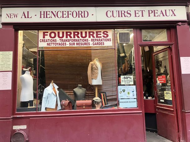 Devanture bordeaux avec des manteaux de fourrure et des peaux exposés en vitrine, et une enseigne indiquant Fourrures