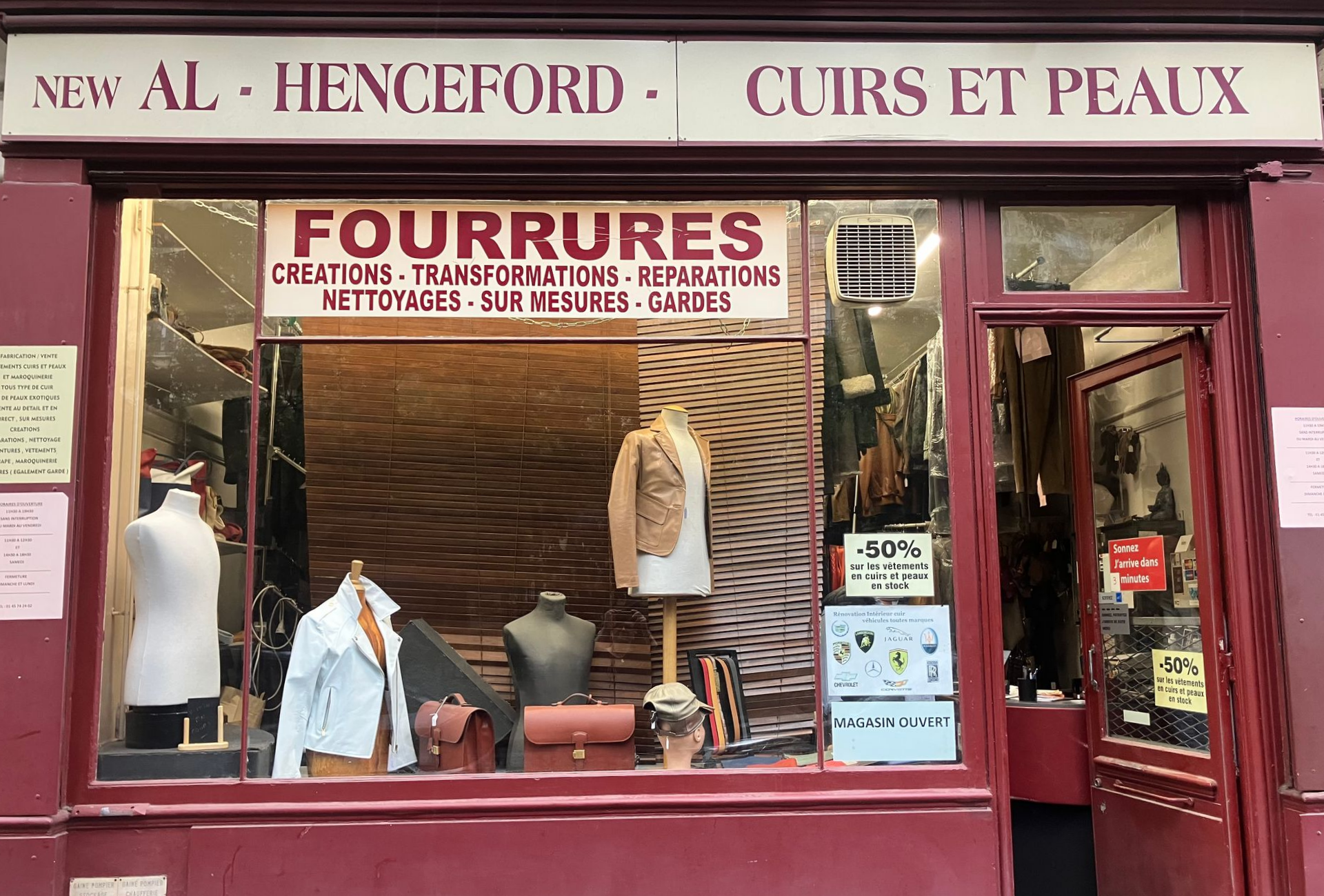 Vitrine bordeaux d’un magasin de manteaux de fourrure, avec des mannequins, des enseignes et une vitrine en verre