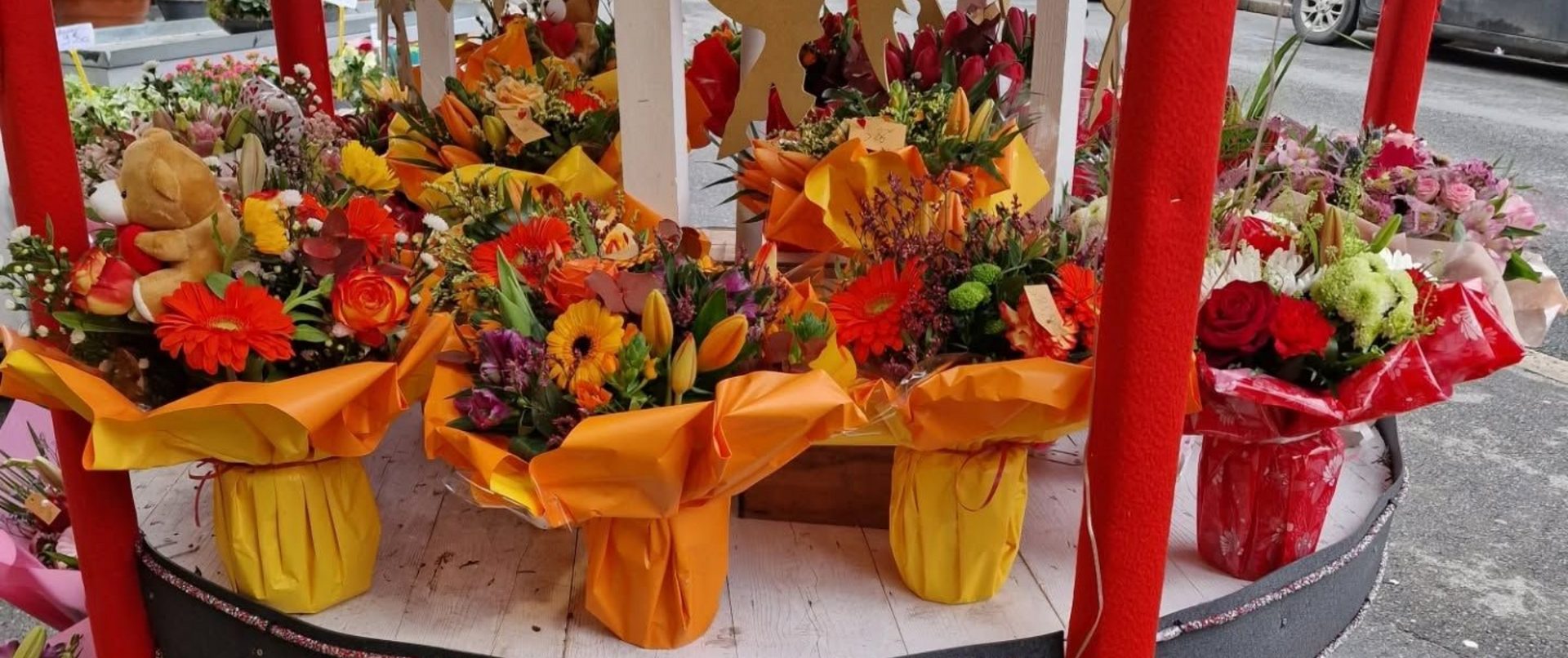 Bouquets de fleurs en papier rouge et jaune sur un chariot.