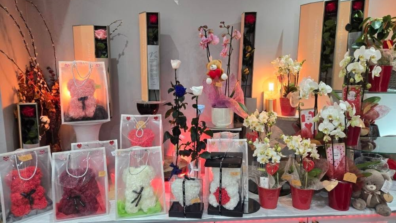 Présentoir de fleuriste présentant des oursons en roses, des orchidées et des roses simples de différentes couleurs.