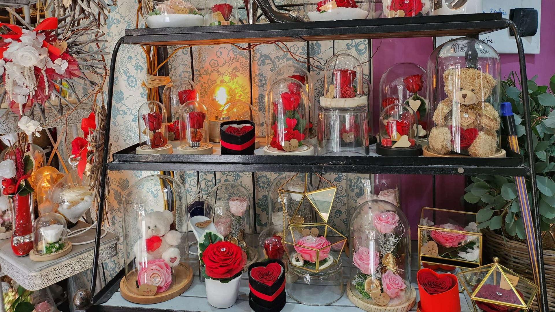 Les étagères présentent des cadeaux de Saint-Valentin : des roses, des ours en peluche et des cœurs décoratifs dans des dômes et des vases en verre.