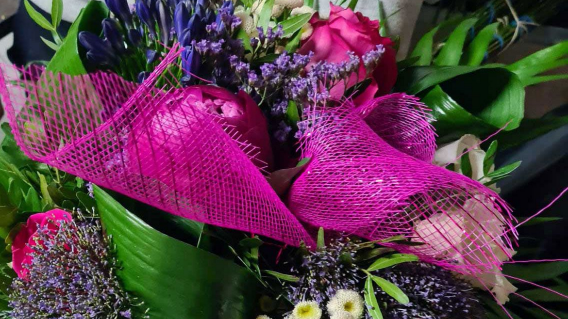 Bouquet de fleurs : roses roses, lavande violette, feuilles vertes et filet rose décoratif.