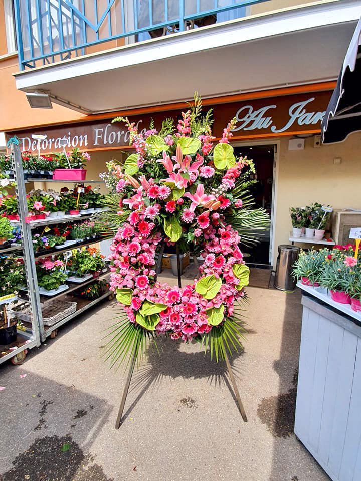 Couronne florale avec des roses roses et des lys, à l'extérieur d'un magasin de fleurs.