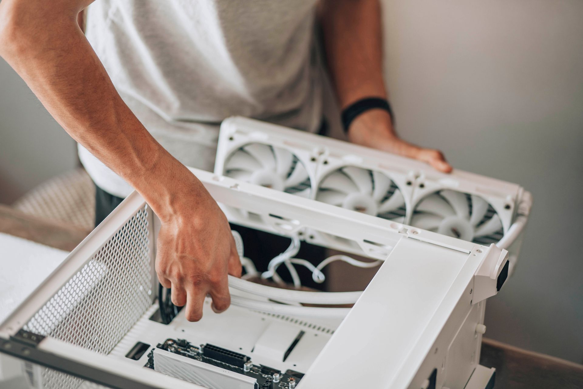 Une personne assemble un ordinateur blanc et place un radiateur à ventilateur dans le boîtier.