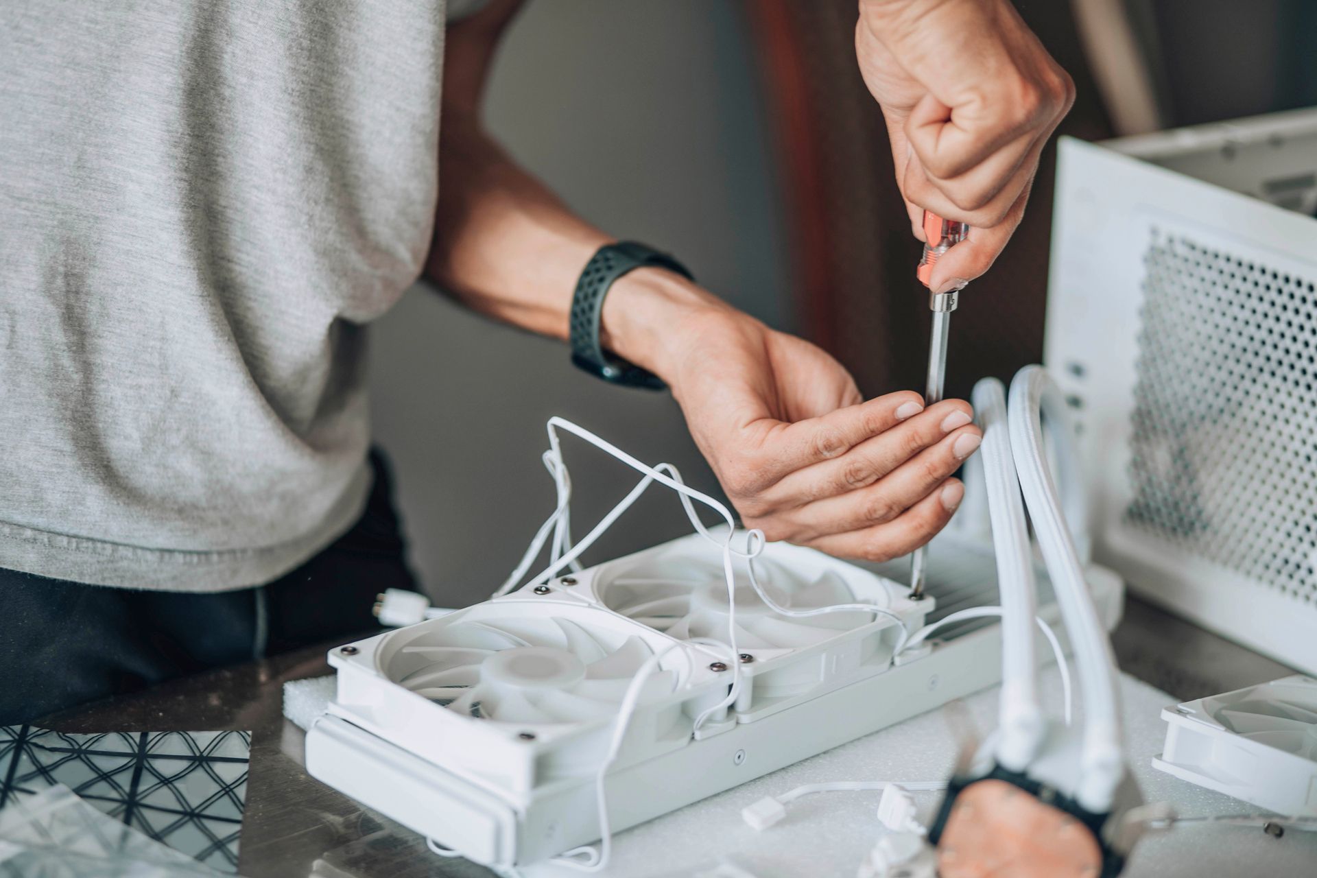 Une personne utilise un tournevis pour assembler un système de refroidissement d'ordinateur blanc.