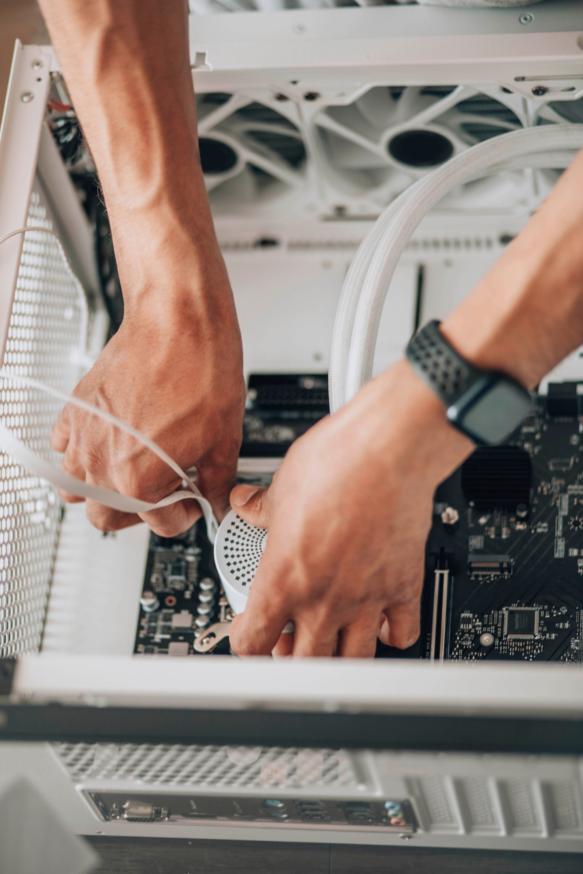 Des mains installent un composant à l'intérieur d'un boîtier d'ordinateur avec des tubes de refroidissement liquide blancs.