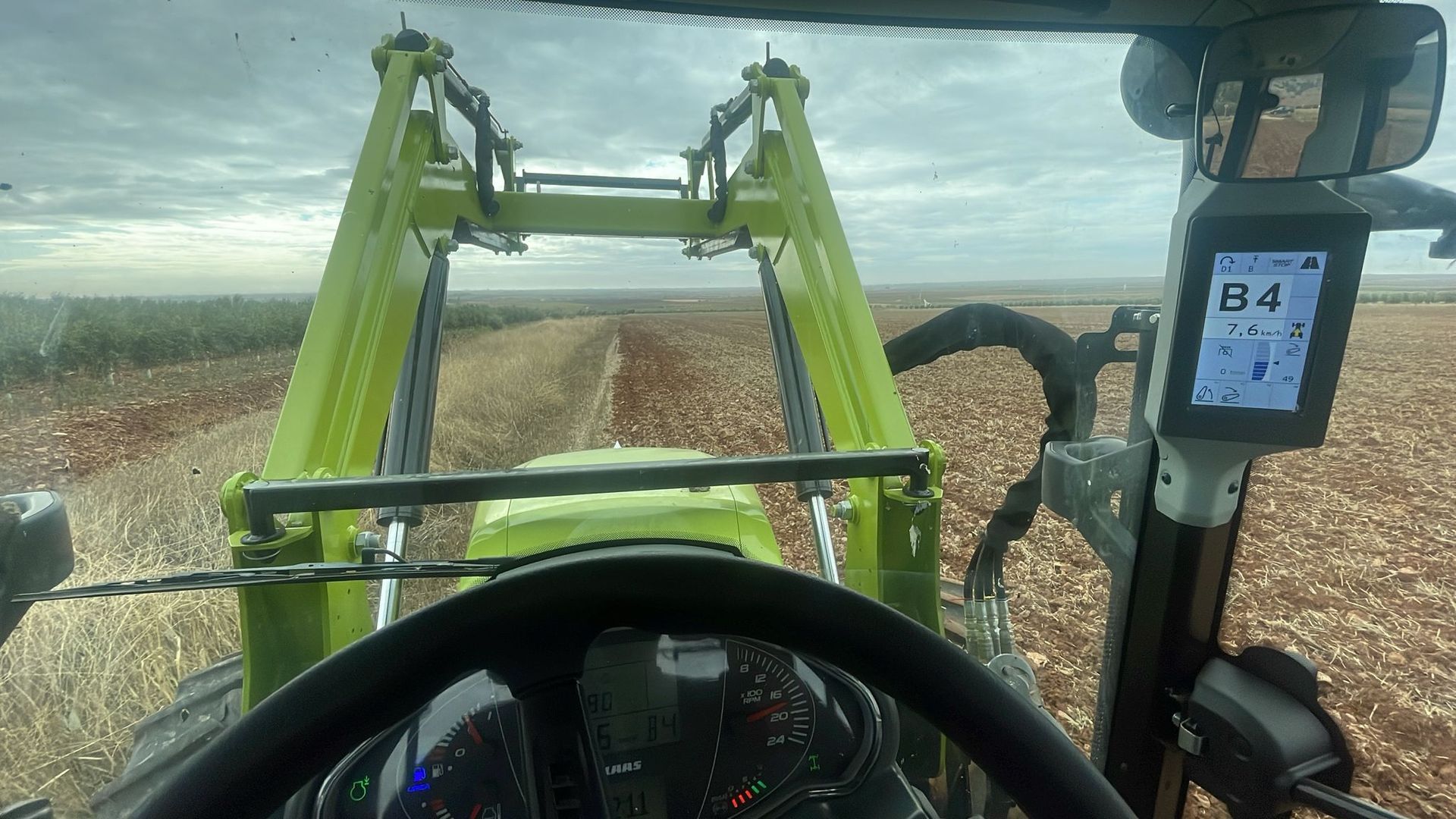 Vista desde la cabina de un tractor que transporta un cubo de patatas recién cosechadas por un campo