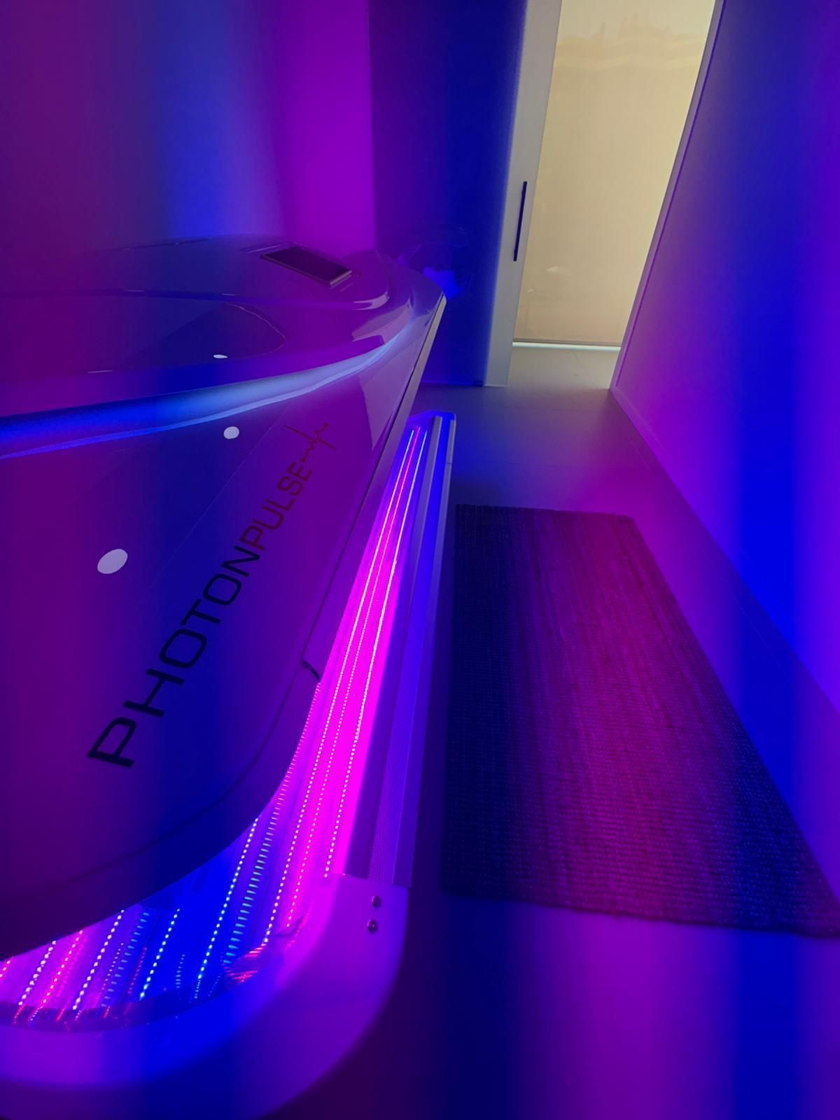 Un dispositivo PhotonPod iluminado con luces azules y rosas en una habitación violeta.
