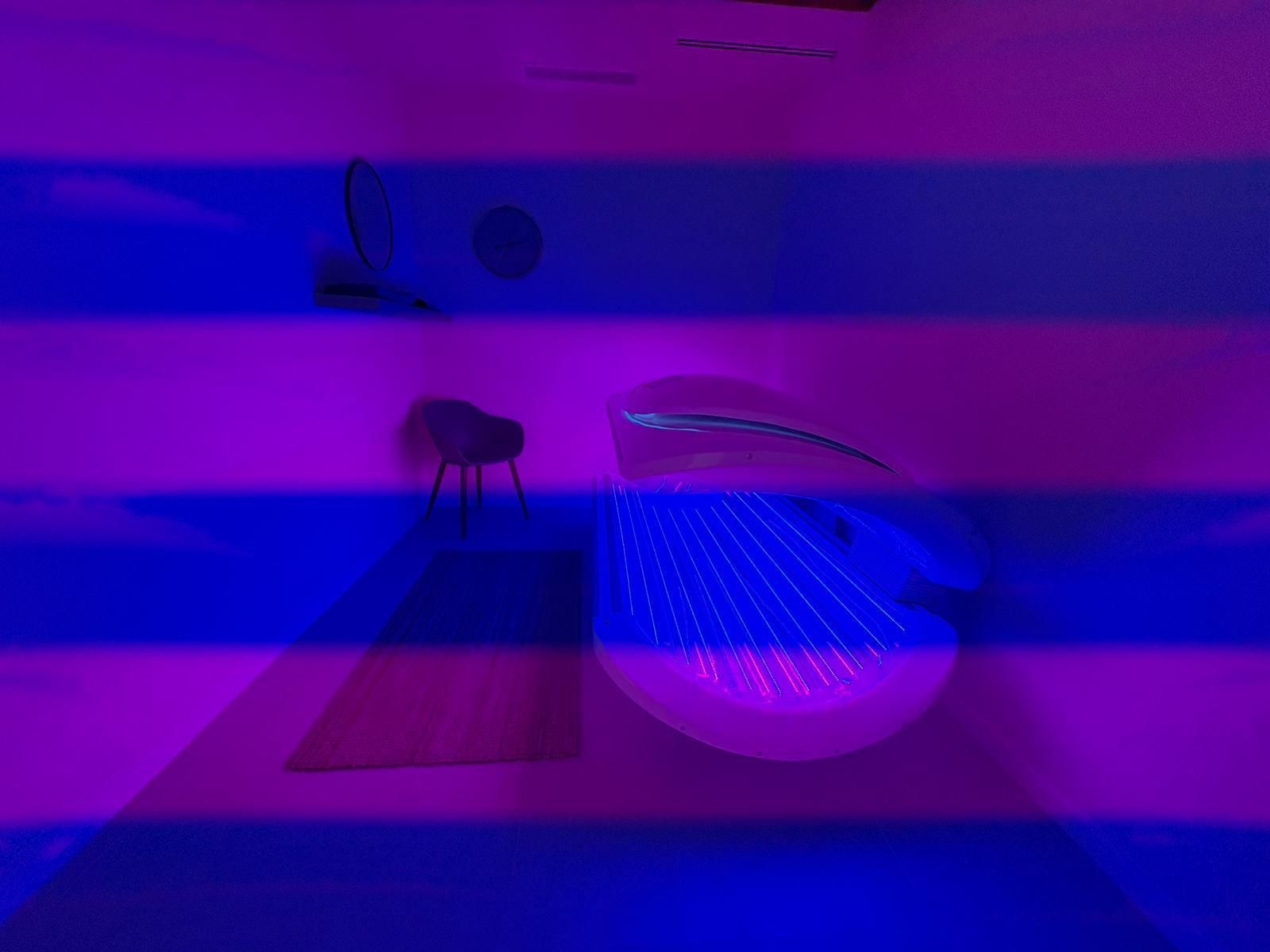 Una bañera iluminada en un baño moderno, con una silla y un espejo visibles. Rayas moradas y azules.