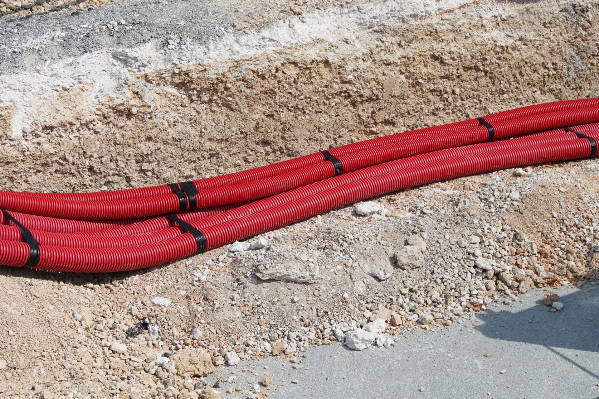 Des tuyaux rouges sont posés sur du gravier.
