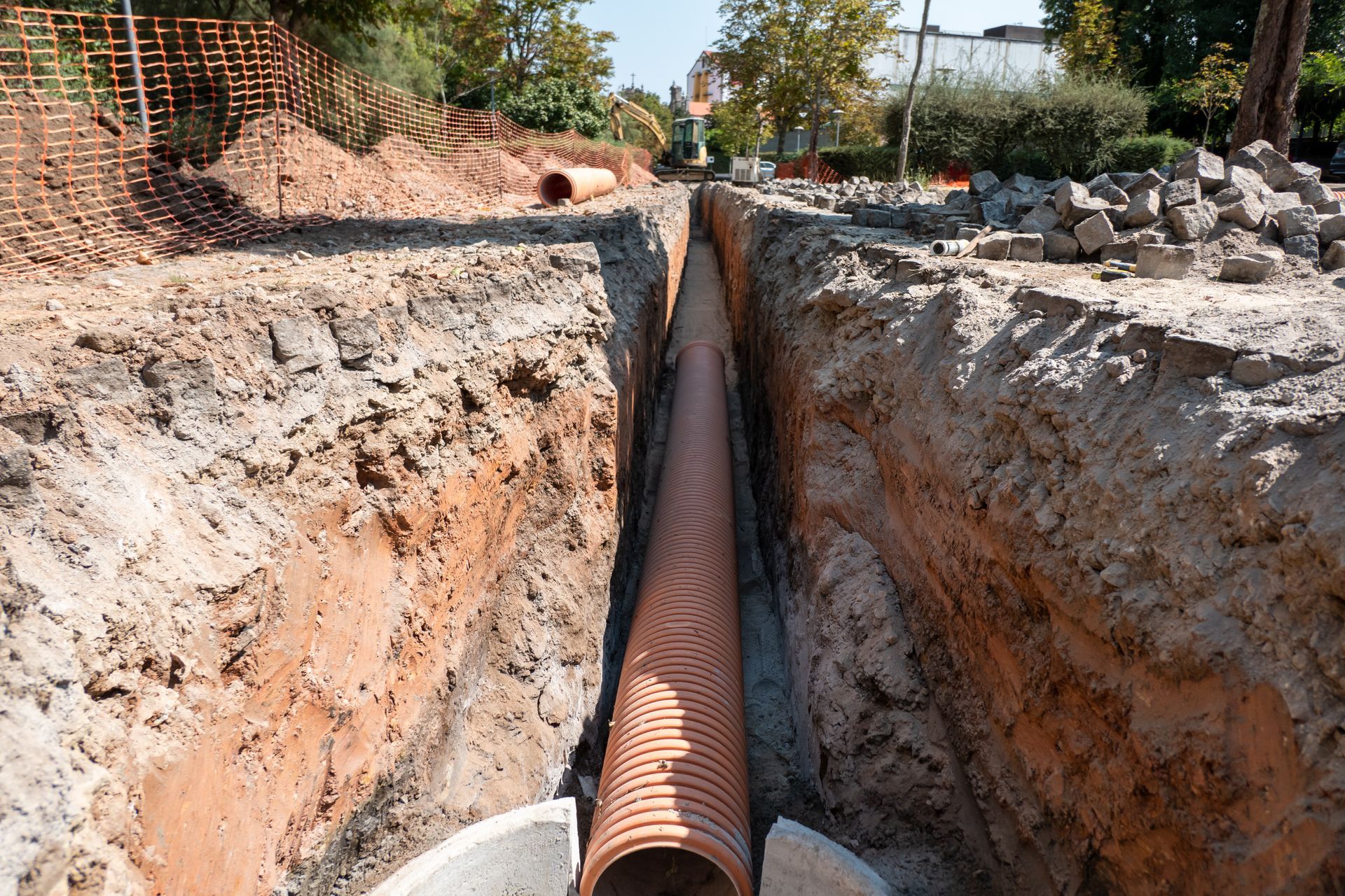 Tranchée avec une grosse canalisation en cours d'enfouissement sur un chantier de construction.