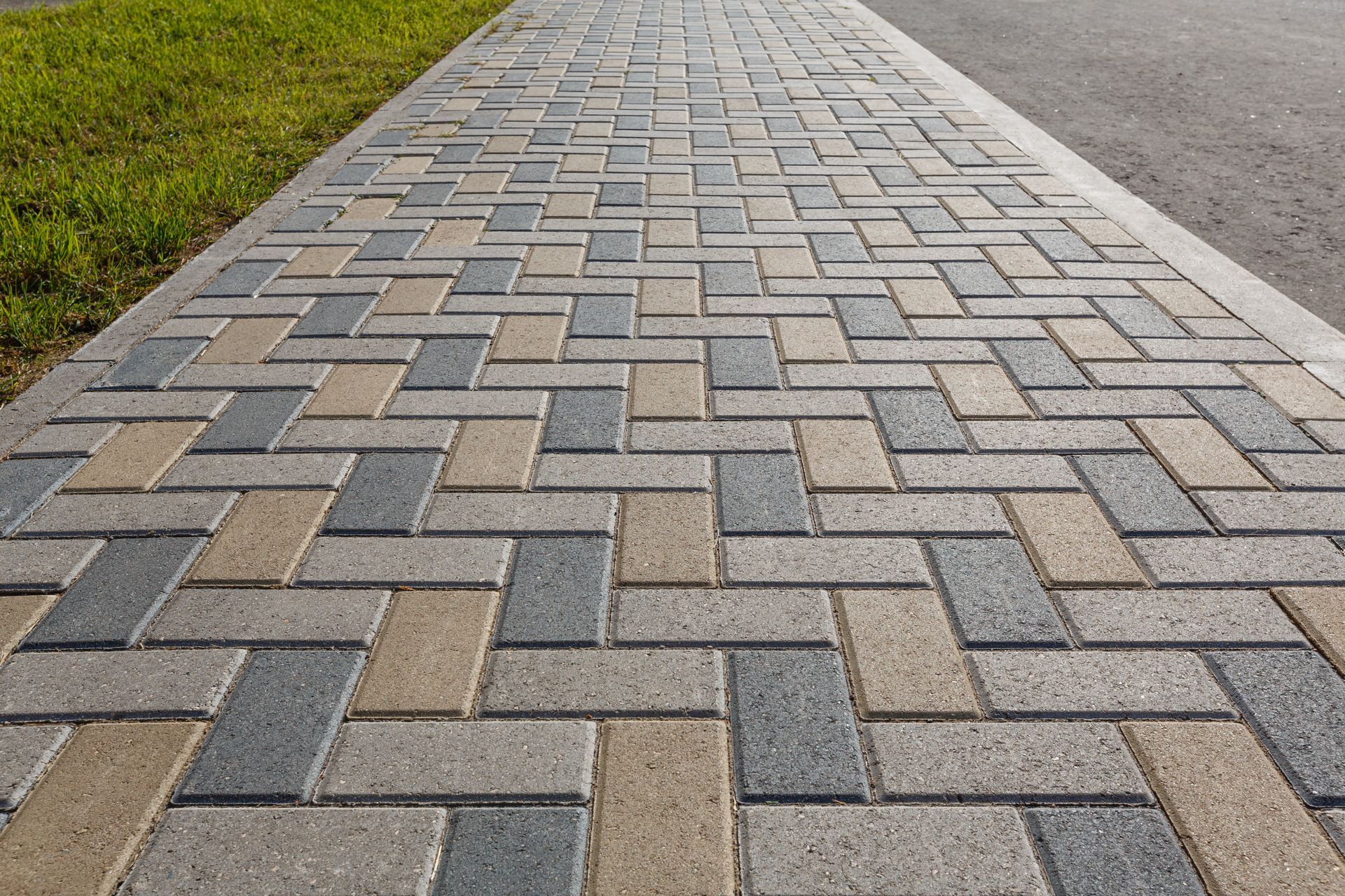 Allée pavée, composée de briques rectangulaires grises et beiges.