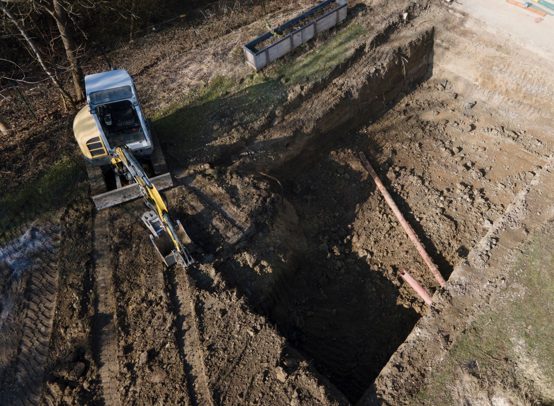 Une excavatrice creuse une grande fosse sur un chantier de construction.