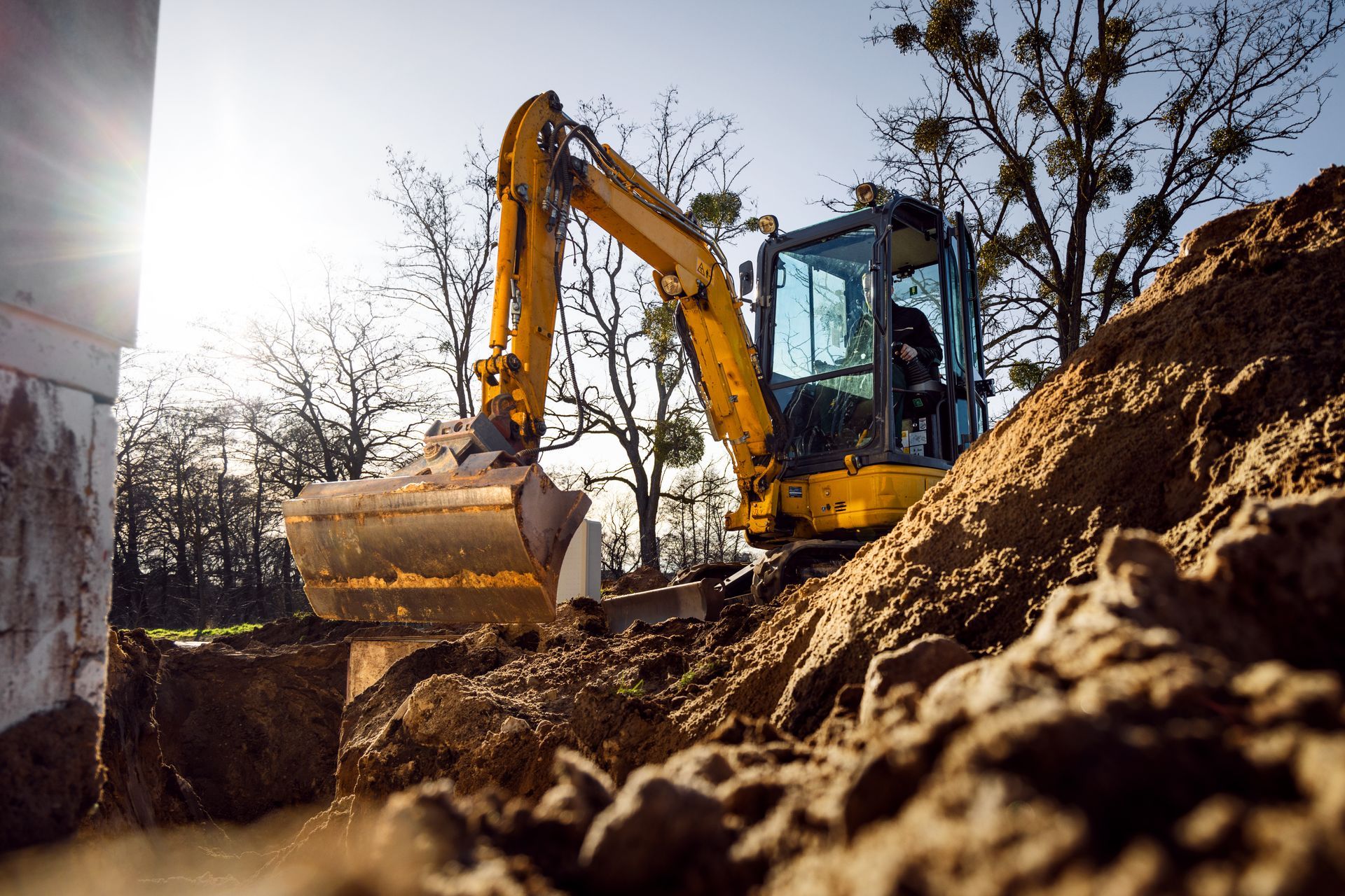 Une pelleteuse creuse un monticule de terre sur un chantier de construction.