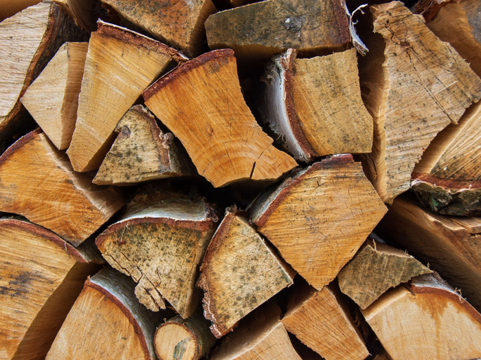 Bûches de bois de chauffage fendues et empilées, au grain de bois beige et brun.