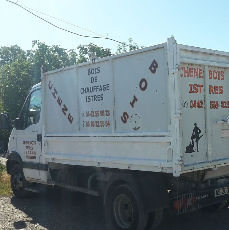 Camion blanc stationné en extérieur sur une route ensoleillée, vue de côté avec inscription en français sur la benne.