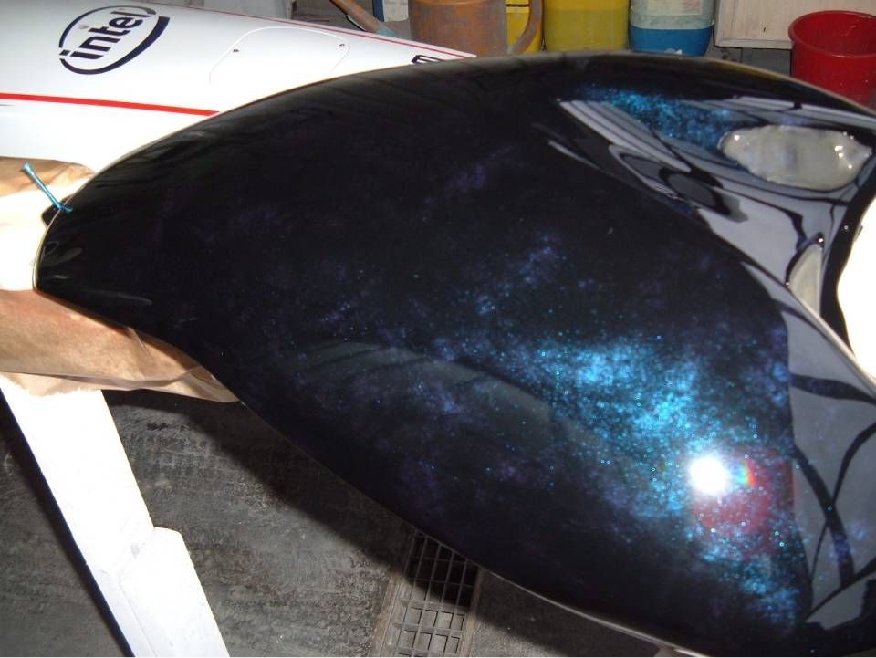 Nahaufnahme eines glänzend schwarzen Motorradteils mit irisierenden blauen und violetten Akzenten; im Hintergrund das weisse Intel-Logo.