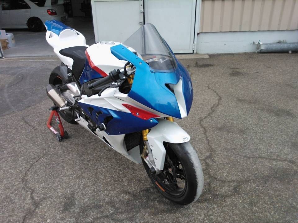 BMW S1000RR Motorrad in blauer, weisser und roter Lackierung, geparkt auf Asphalt.