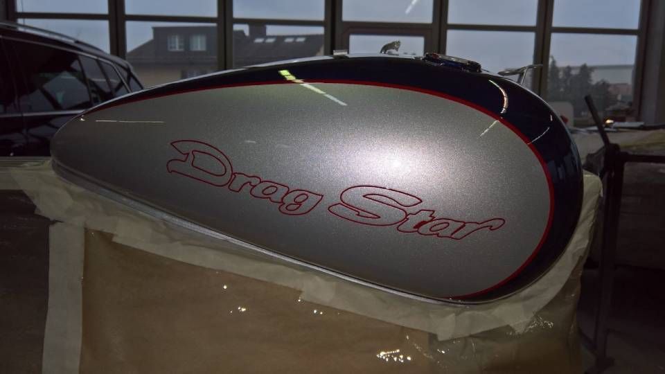 Silberner Motorrad-Benzintank mit dem Schriftzug „Drag Star“ in Rot und dunkelblauen Akzenten.