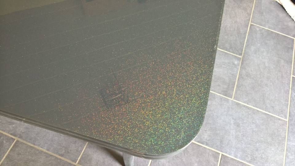 Graue Arbeitsplatte mit irisierenden Sprenkeln, abgerundete Ecken und gefliester Boden.