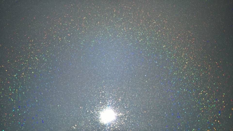 Helles Licht, umgeben von verstreutem Glitzer auf dunklem Untergrund.