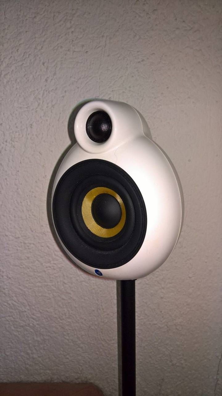 Weisser Lautsprecher mit abgerundetem Design, schwarzem Standfuss und gelben und schwarzen Lautsprecherelementen.