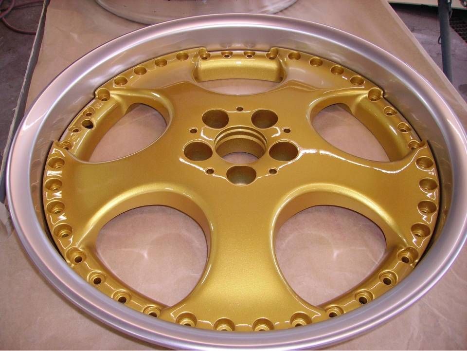 Goldlackierte Autofelge mit silbernem Felgenhorn.