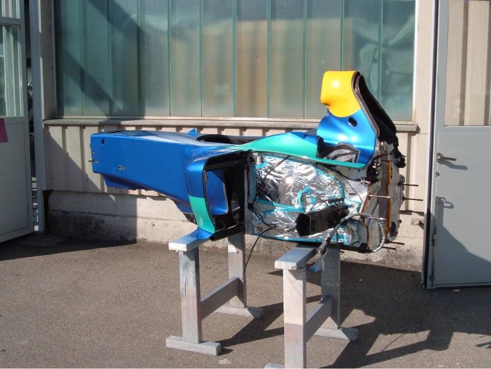 Blaue und gelbe Fahrzeugkarosserie auf einem Ständer im Freien.