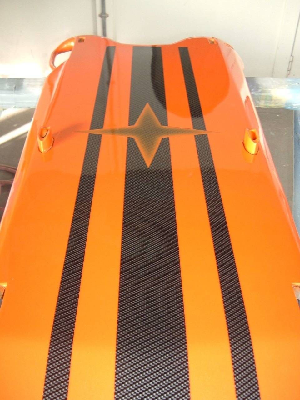 Orangefarbenes Objekt mit schwarzen und goldenen Streifen und einer rautenförmigen Struktur.