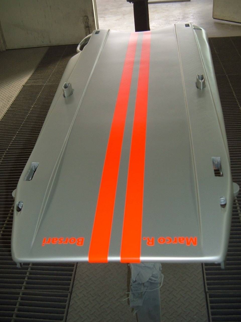 Silbernes Autoteil mit zwei orangefarbenen Rennstreifen.