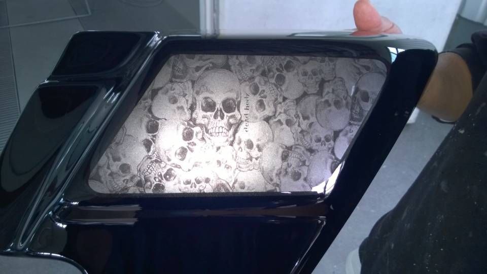 Schwarze Motorradsatteltasche mit Totenkopfmotiv an der Seite, die von einer Person gehalten wird.