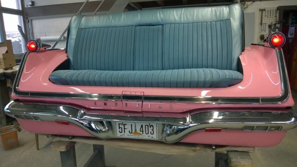 Rosa Sofa in Autoform mit türkisfarbener Sitzfläche und Rückenlehne, Chromstossstange, Rückleuchten und Kennzeichen „5FJ 403“.