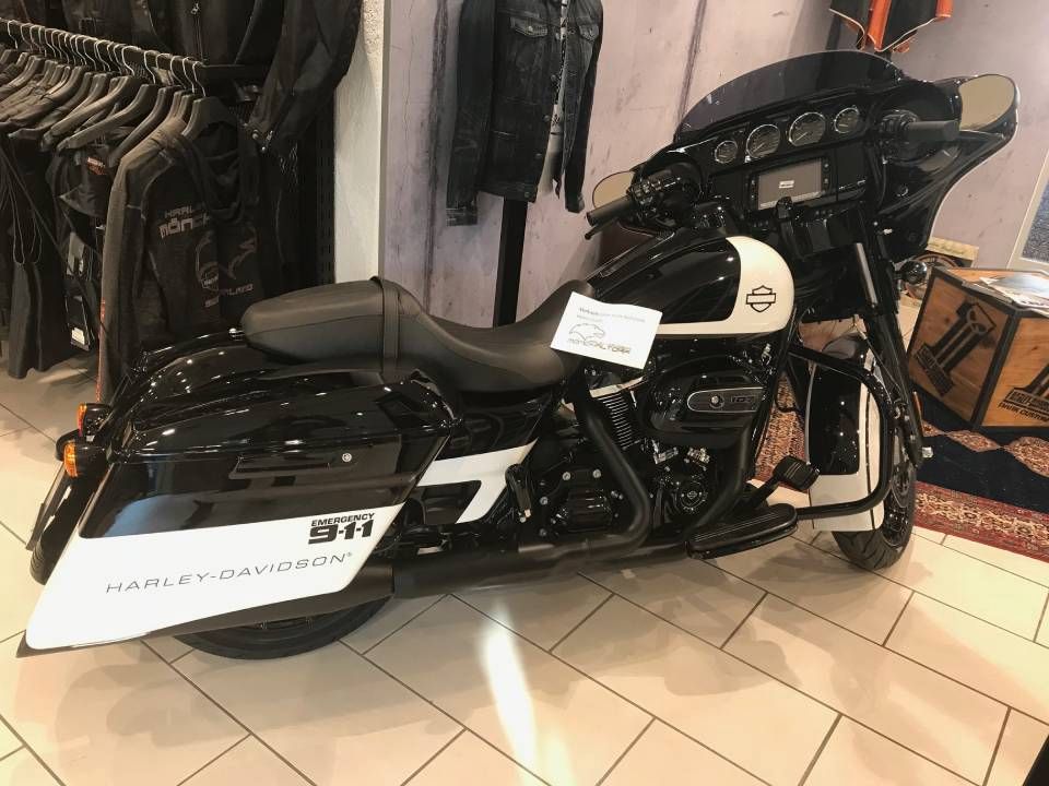 Schwarz-weisses Harley-Davidson-Motorrad in einem Ladenambiente, mit Seitentaschen und Verkleidung.