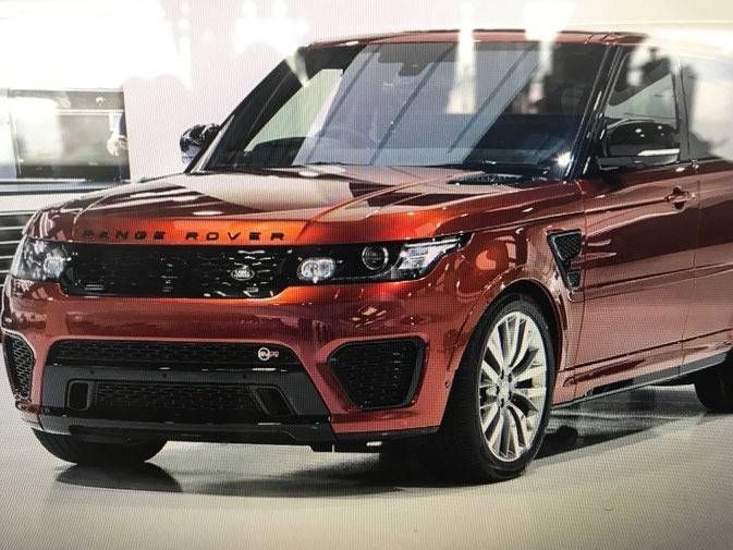 Orangefarbenes Range Rover Cabriolet-SUV, in einer Garage geparkt, Vorderansicht.