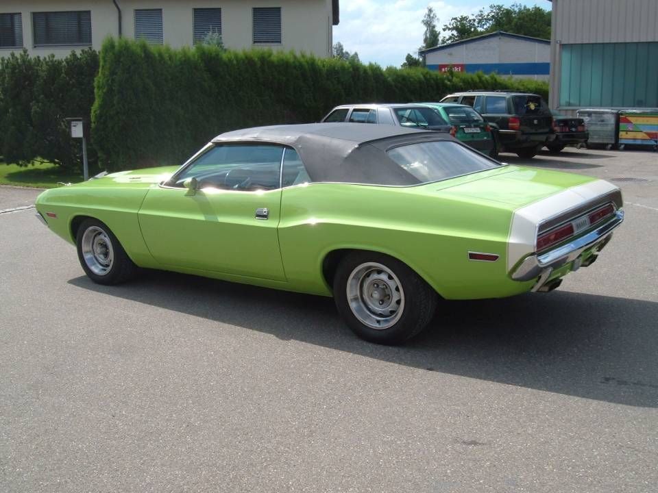 Ein grünes, klassisches Dodge Challenger Cabriolet parkt auf dem Bürgersteig.