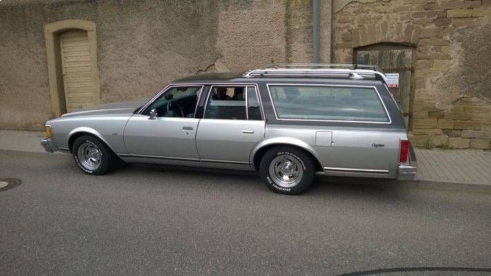 Ein silberner Kombi parkte auf einer Strasse vor einem Steingebäude mit dunklem Dach.