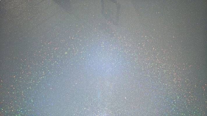 Graue Oberfläche mit verstreuten, glitzernden weissen Sprenkeln, möglicherweise eine strukturierte Wand oder ein bemalter Hintergrund.